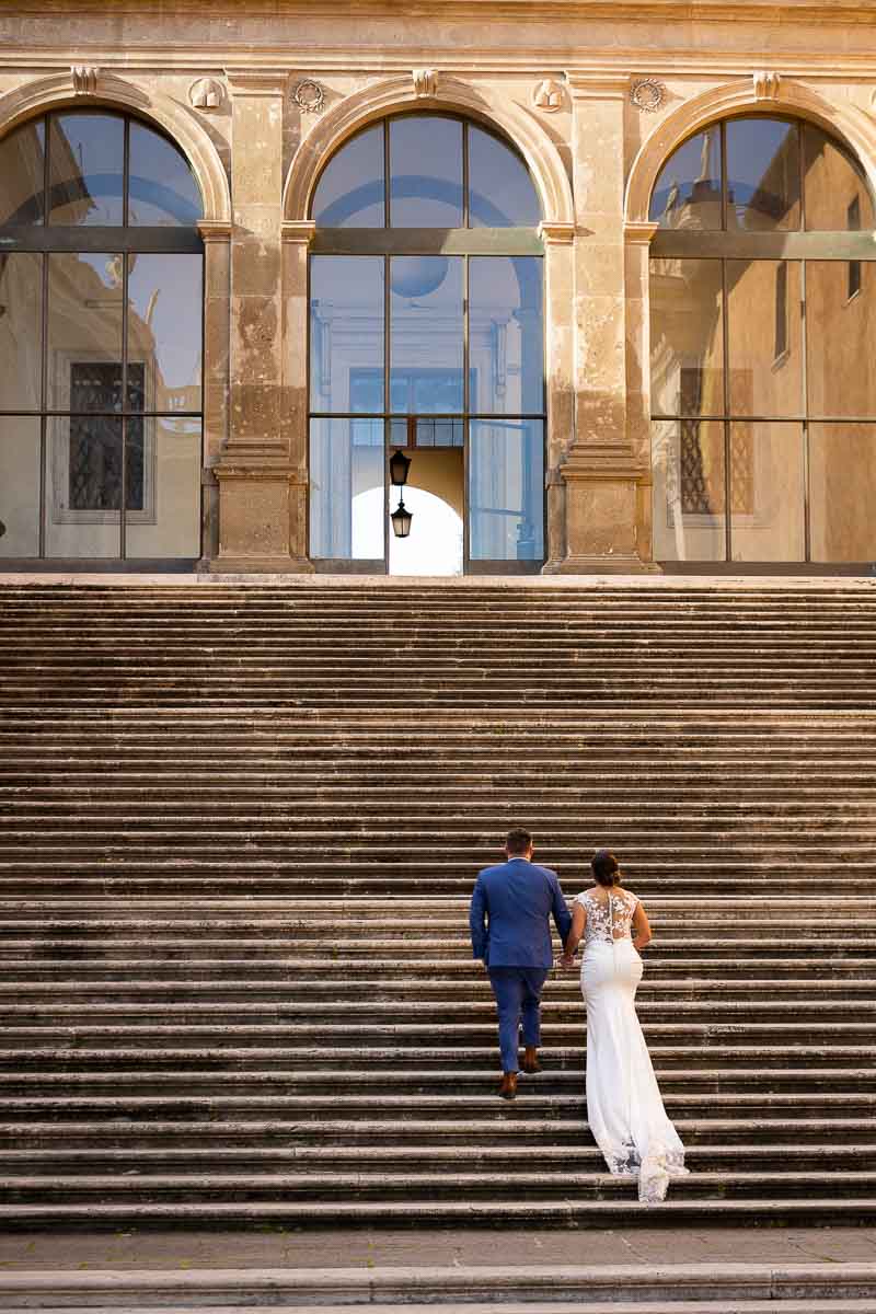 Groom and bride walking up the steps of a large staircase during their photography session 