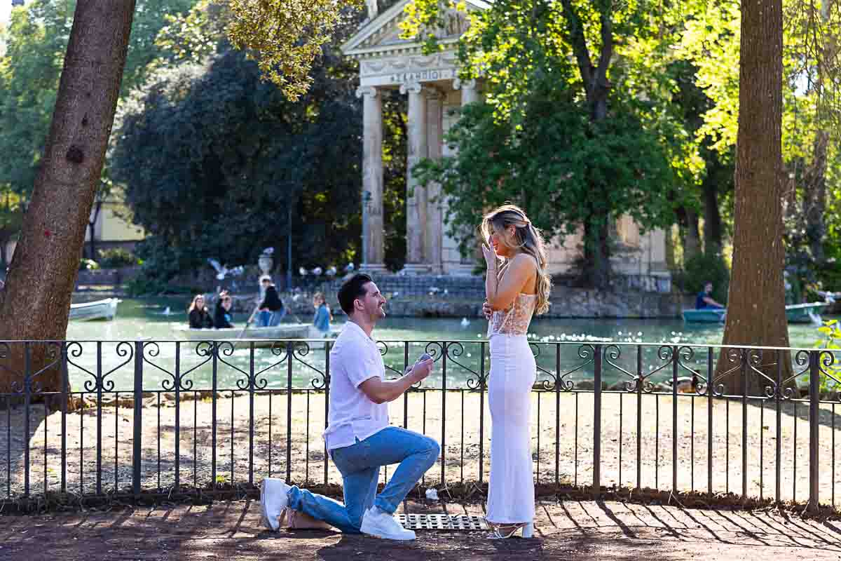 Man kneeling down during the proposal moment in the Villa Borghese location by the lake side