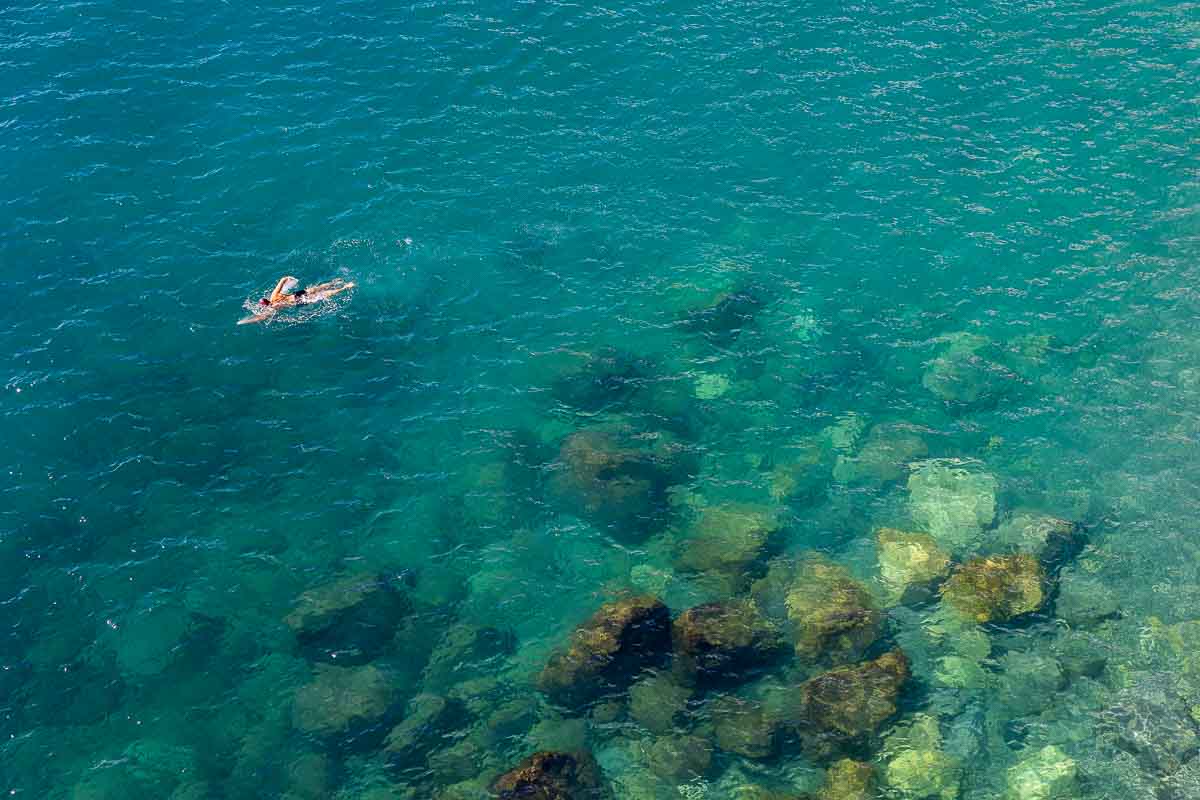 Swimming in the azure emerald green water of the coast seen from up above 