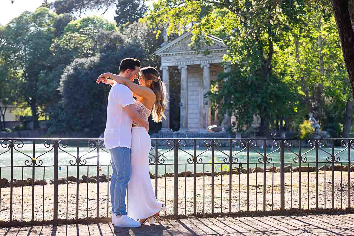 Couple taking pictures together in the park by the water side of Borghese lake