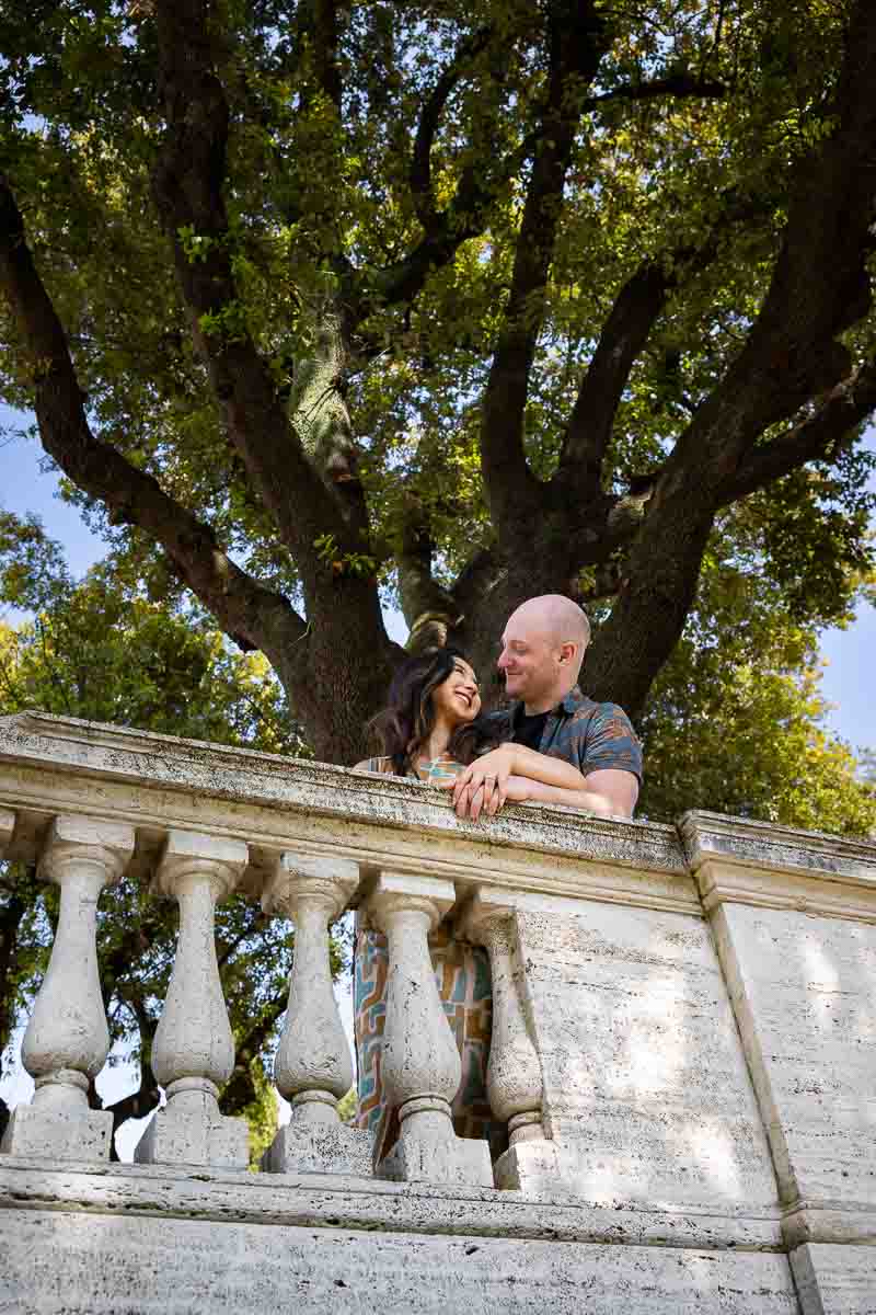 Shooting engagement pictures at the Villa Borghese park in Rome with green trees in the backdrop 