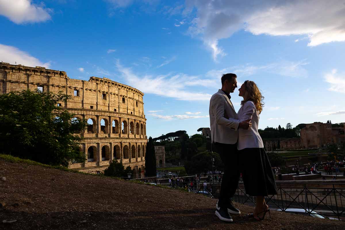 Photo shooting at the Roman Colosseum as silhouettes emerge from the sun setting with bright vivid colors. Best Coupe photography in Rome