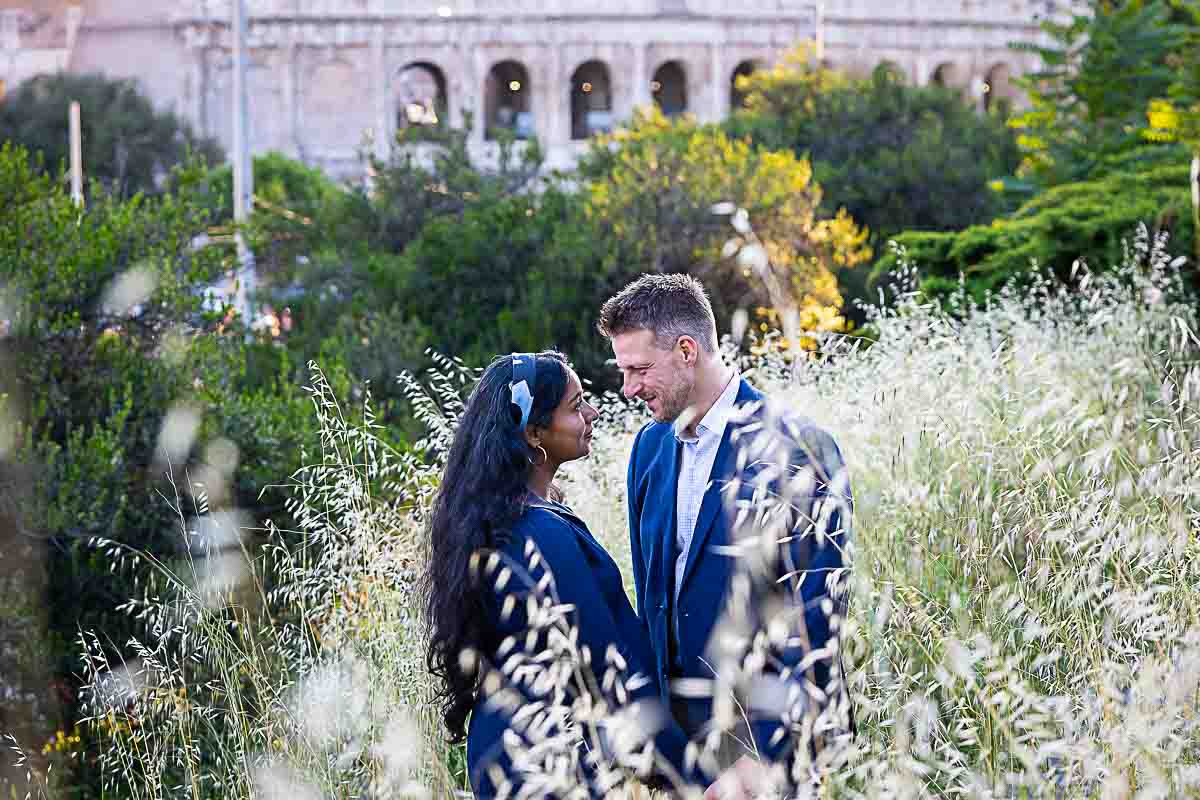 Picture of an engaged couple standing together posed with the Colosseum in the background after a proposal photoshoot 