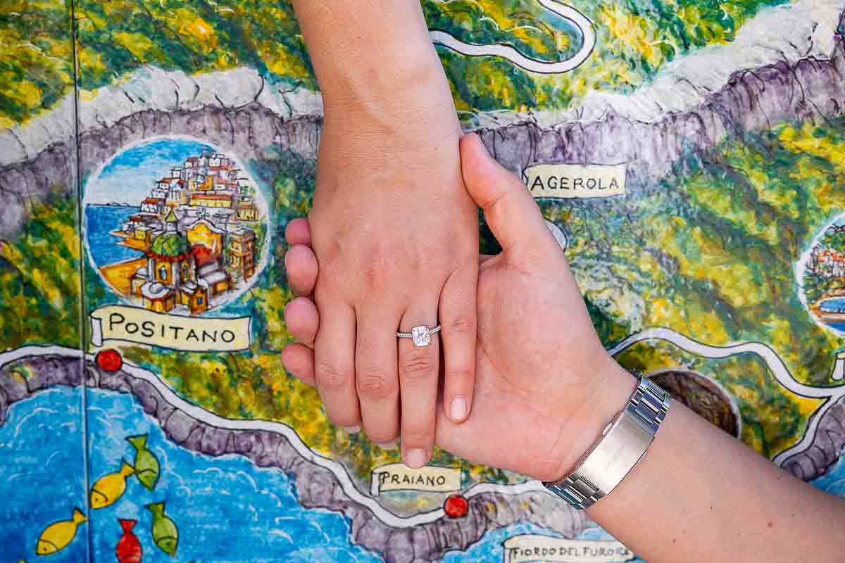 Holding hands showing off the engagement ring revealing the map of the Amalfi coast on a ceramic surface 