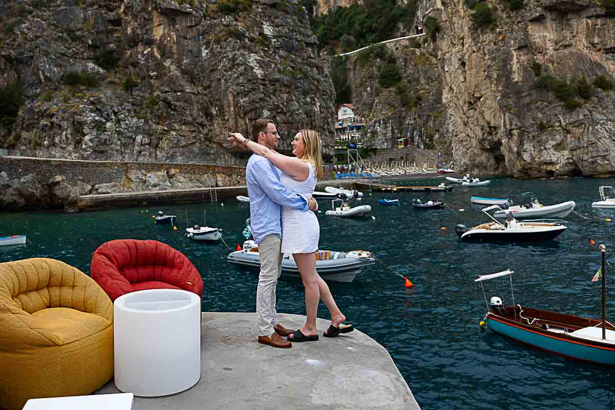 Pose couple portrait by the water edge with boats floating on the water 