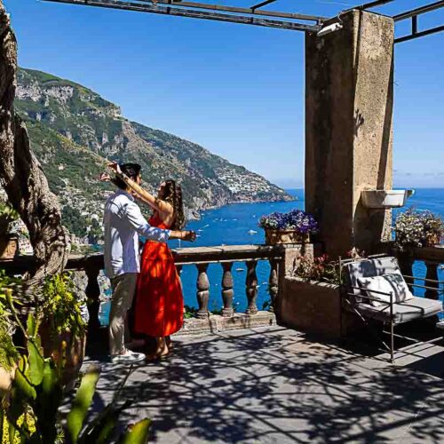 Wide-angle view of a couple celebrating their engagement on a panoramic terrace overlooking the southern Italian coastline