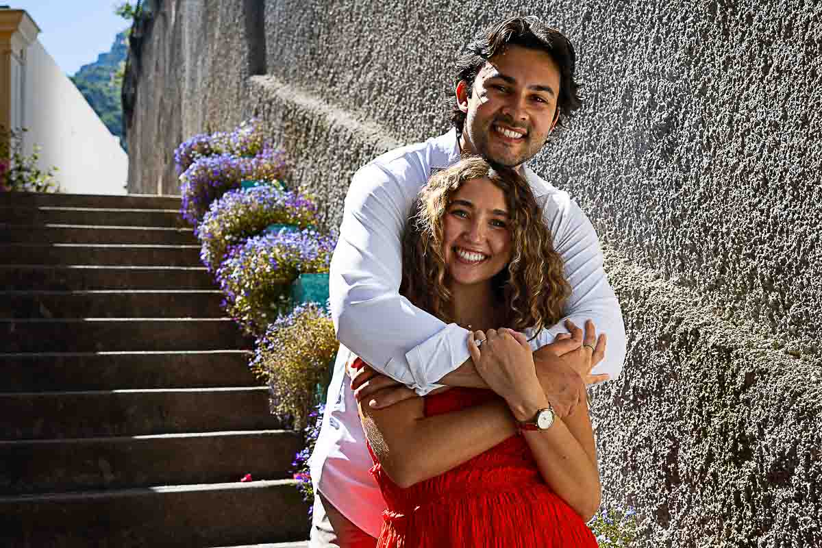 Couple sharing an intimate embrace on a charming stone staircase adorned with vibrant flowering plants