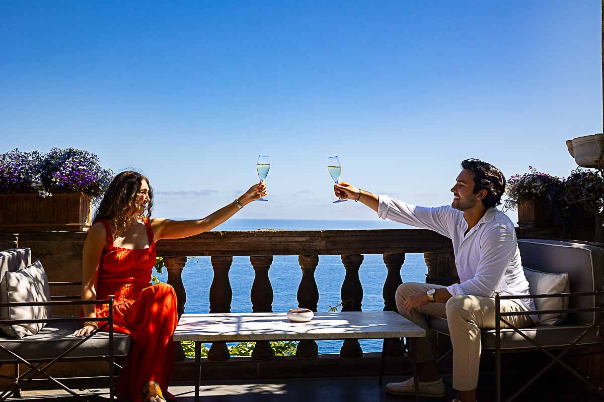 Engaged couple raising glasses in a joyful toast, captured by expert Positano Proposal Photographer session specialists during a romantic photo session