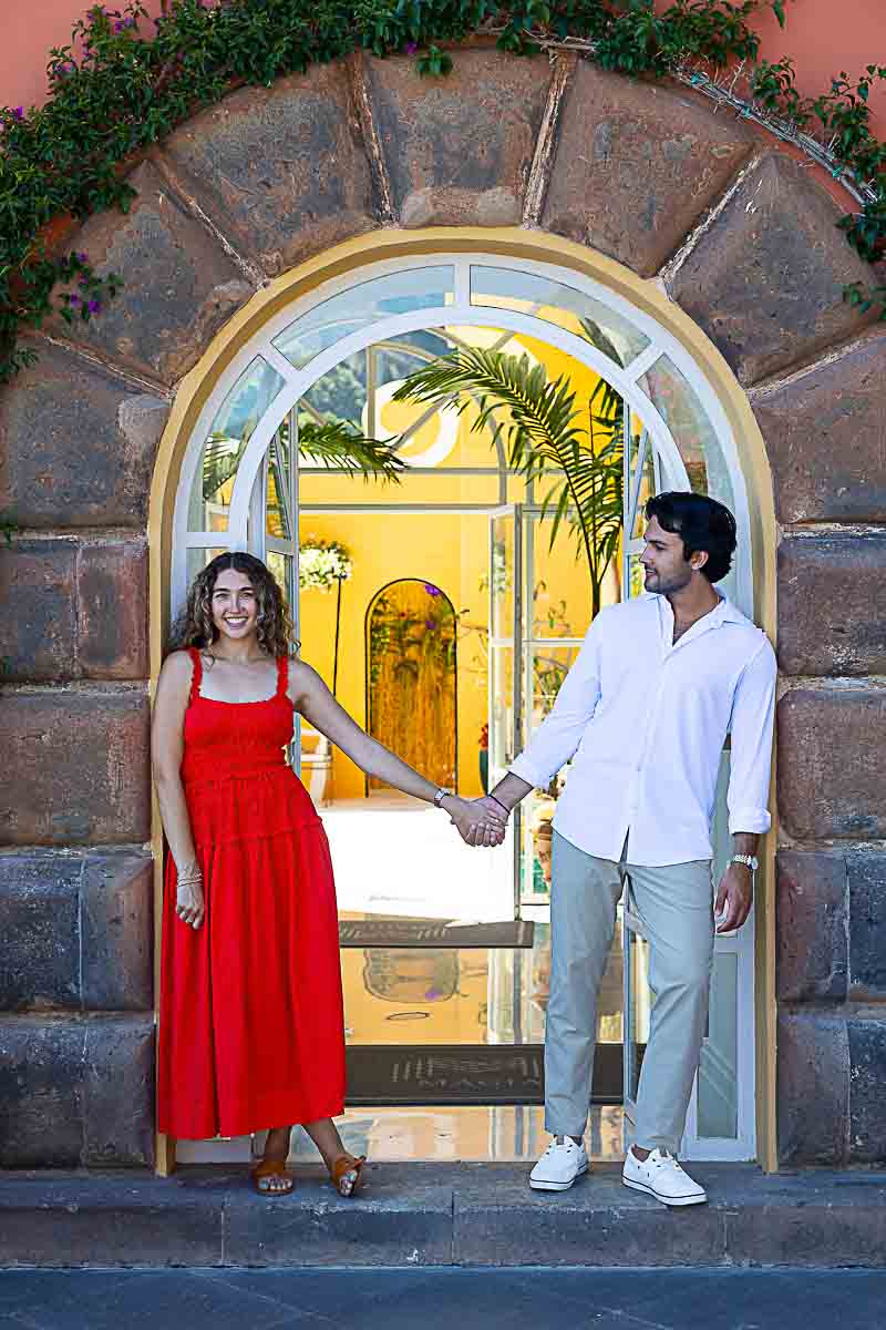 Posed couple standing gracefully in front of a charming villa doorway, photographed during a professional portrait session