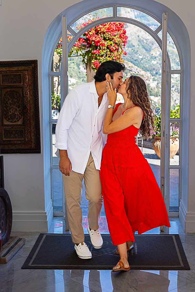Couple sharing a tender kiss while walking hand in hand along a picturesque coastal path during their romantic photo session