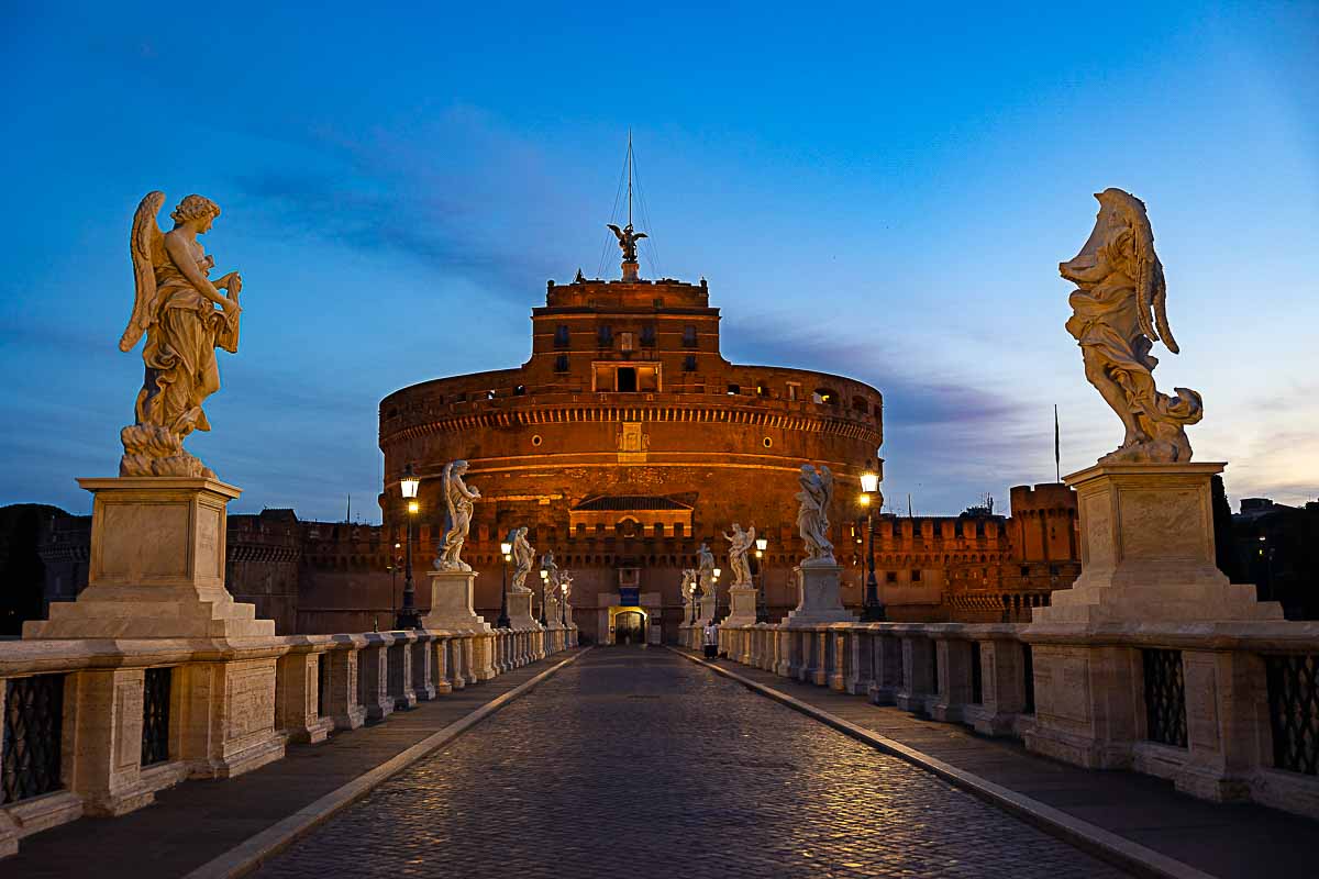 Castel Sant'Angelo bridge with sunrise light glowing through the horizon 