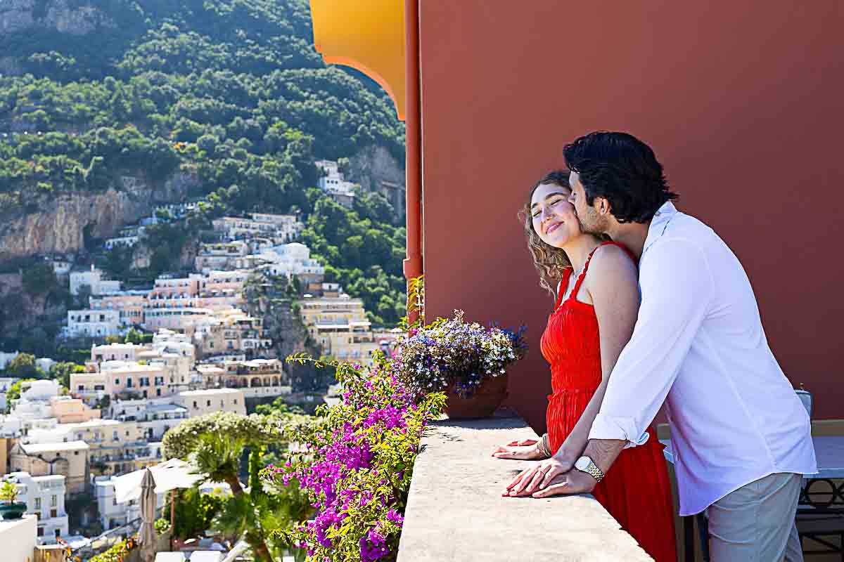 Side view of an affectionate couple captured during a romantic portrait session, with the scenic hillside town as their backdrop