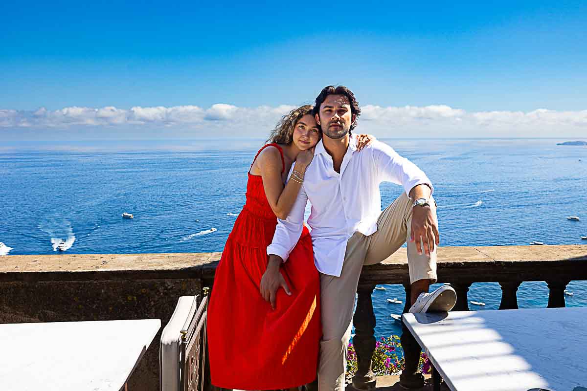 Direct candid snapshot of a relaxed couple standing together by the sea along the Amalfi coastline, captured during a relaxed photo shoot