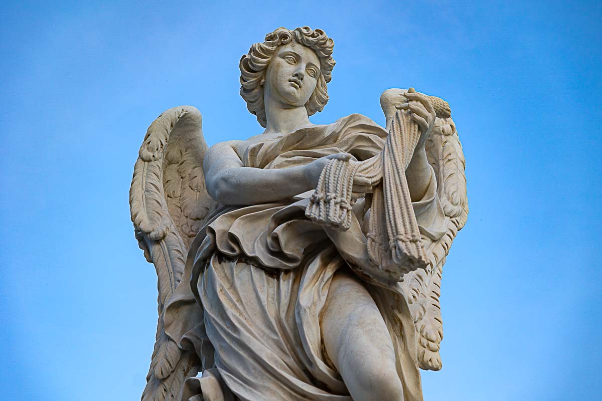 Marble statue of an angel on the bridge with blue sky in the background 