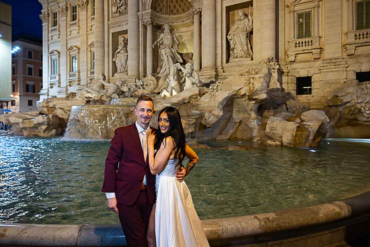 Picture taking at the Trevi fountain with a wedding couple posed to take pictures during a nighttime photo shoot in Rome 