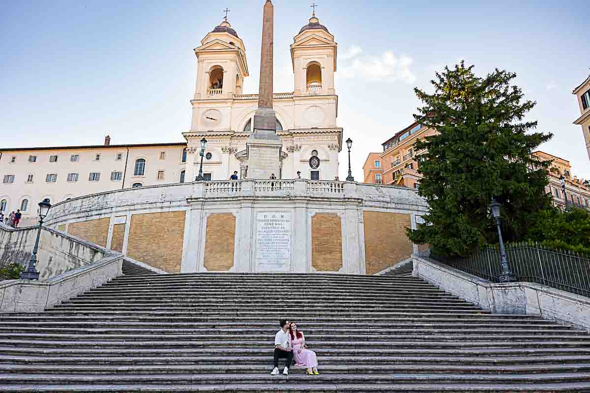 Couple seated on the Spanish Steps captured in early morning light during engagement shoot.