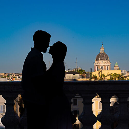 Silhouetted couple looking over Rome from Parco del Pincio terrace at sunrise.