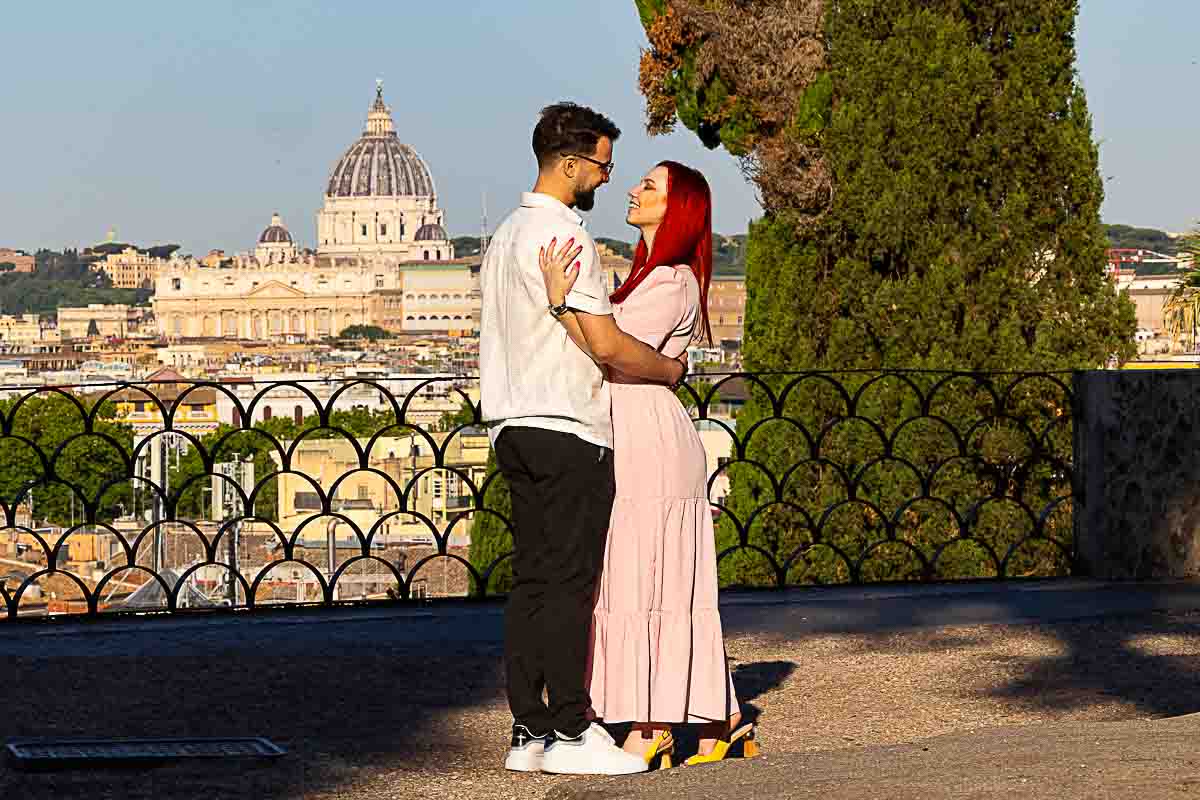 Engagement photo at Parco del Pincio with panoramic Rome skyline in golden morning light. 