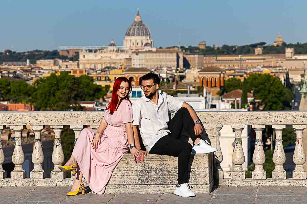 Couple standing at Parco del Pincio overlook during a sunrise photography session with city skyline in background. 