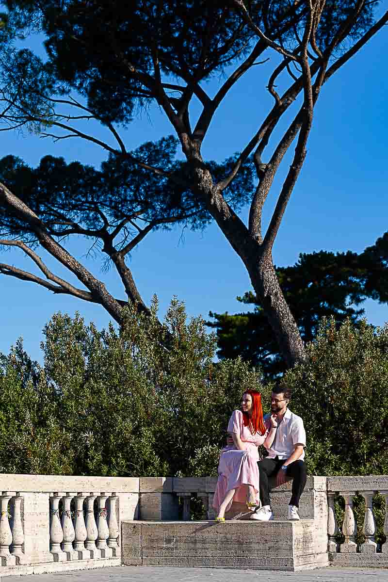 Couple sitting under trees in Parco del Pincio during sunrise photo session