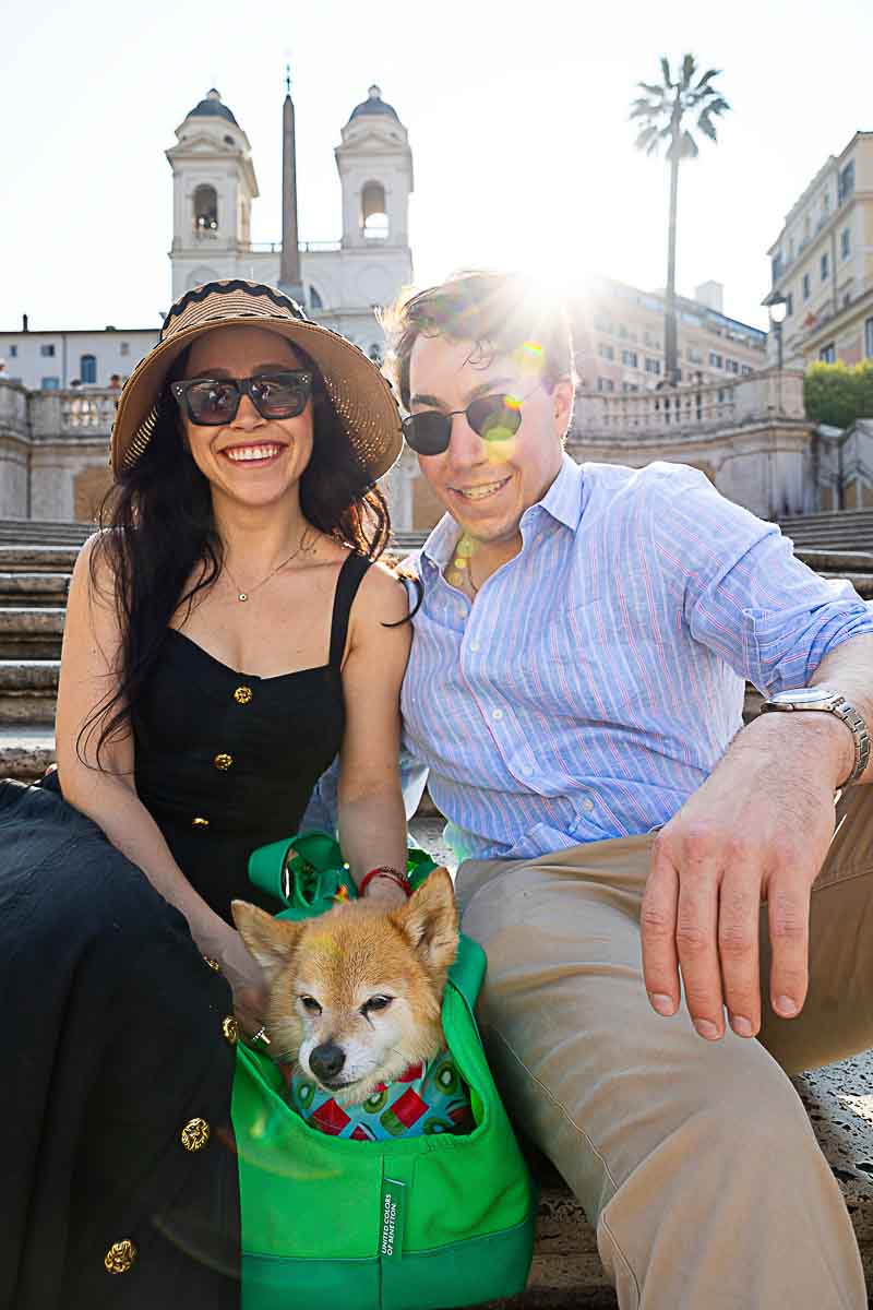 Couple portrait with dog in a green bag laid down in between a family photo 
