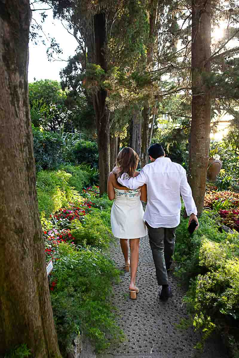 Walking together next to one another in the villa's garden among trees and plants with flowers and other natural ornaments 