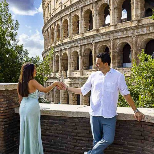 Holding hands while being photographed by Coliseum in the heart of the ancient city: Rome