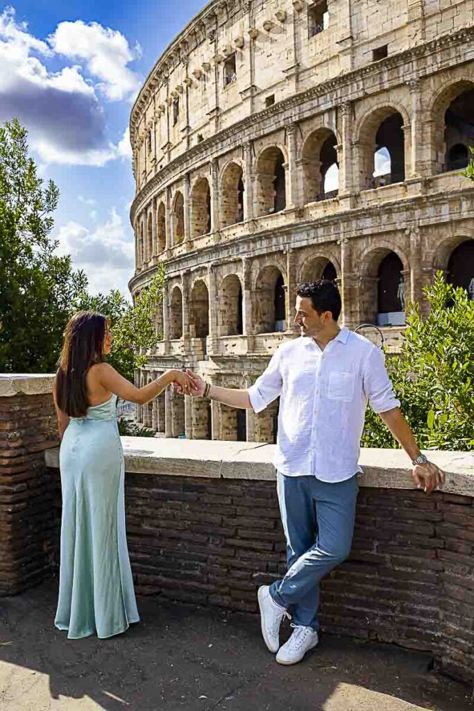 Holding hands while being photographed by Coliseum in the heart of the ancient city: Rome