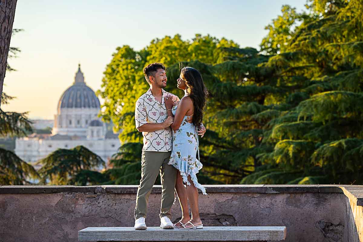 Engagement photography after the proposing while standing on a marble bench before the fantastic view of Saint Peter's cathedral in the far distance 
