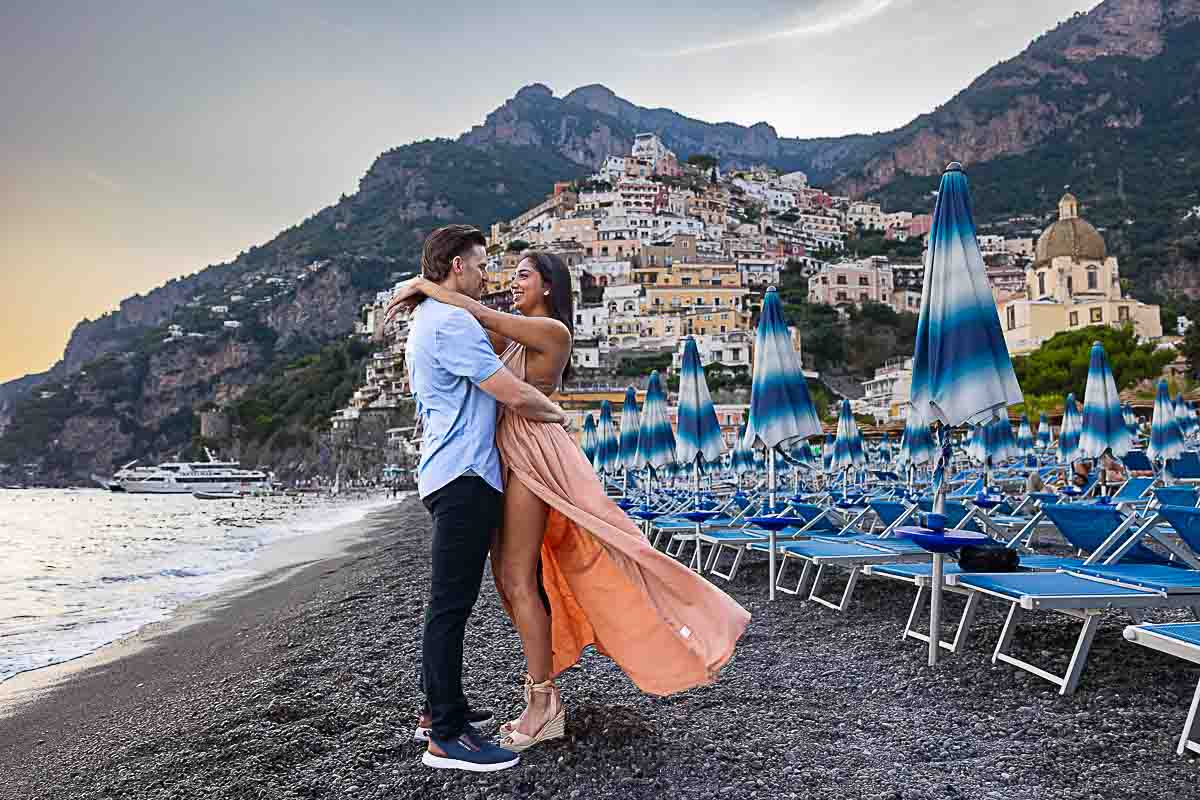 Engagement photography of a couple photographed on the beach of Positano photoshoot with the beach and the umbrellas in the background 