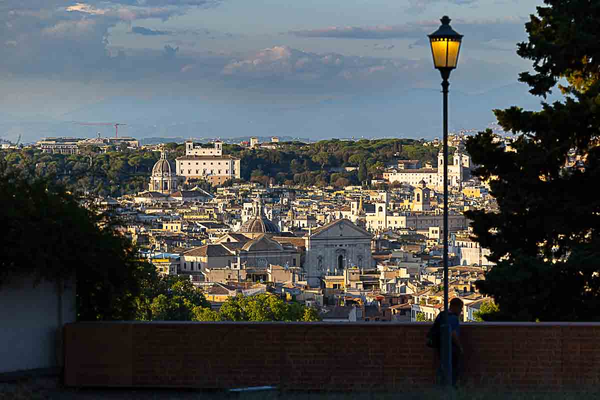 Roman skyline view of all the buildings and horizon while sun is setting down into evening and blue hour dusk 