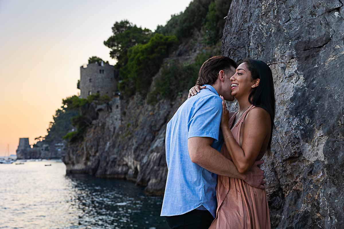 Travel engagement photo session on the Amalfi coast while taking photography pictures by the rocks and the coastal views at sunset
