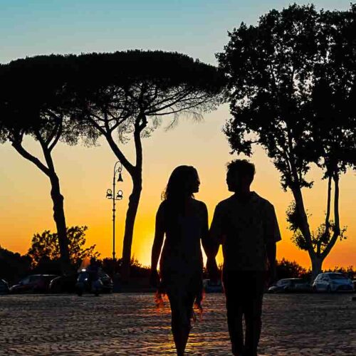 Silhouette couple walking in Piazza Garibaldi on the Janiculum hill under the mediterranean trees rising above our subjects of photography