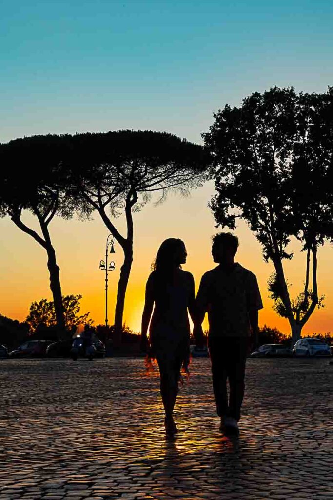 Silhouette couple walking in Piazza Garibaldi on the Janiculum hill under the mediterranean trees rising above our subjects of photography