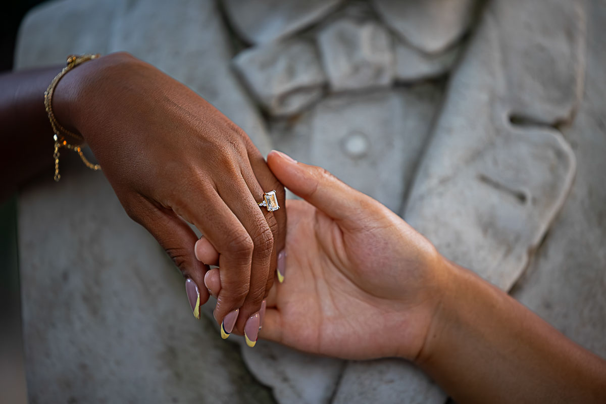 A nice picture of an engagement ring held hand in hand while worn on the finger received after a wedding marriage proposition asked with surprise 