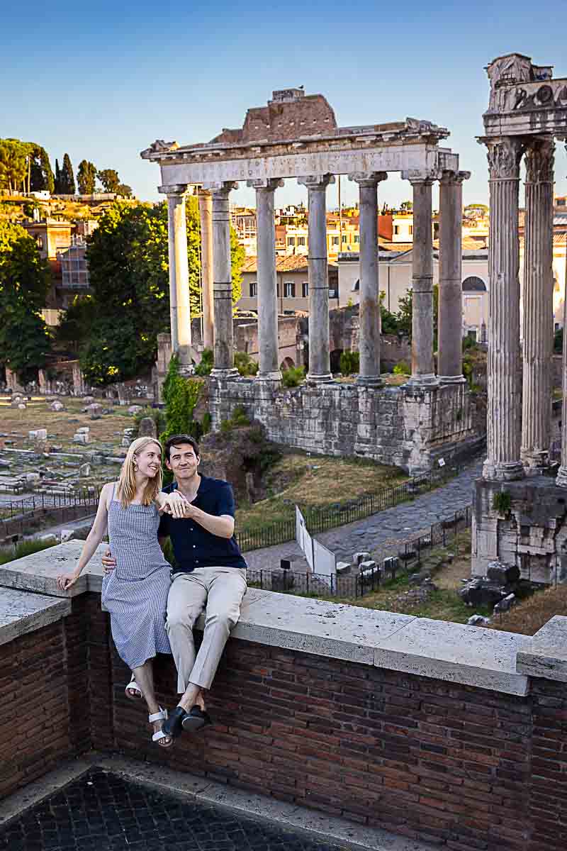 Final portrait picture of a couple showing off the engagement ring while sitting before the temple during a photography session 