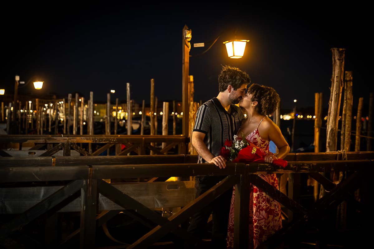 Venice photographer session by the docks at night under warm lighting from a light post with parked boats in the pier 