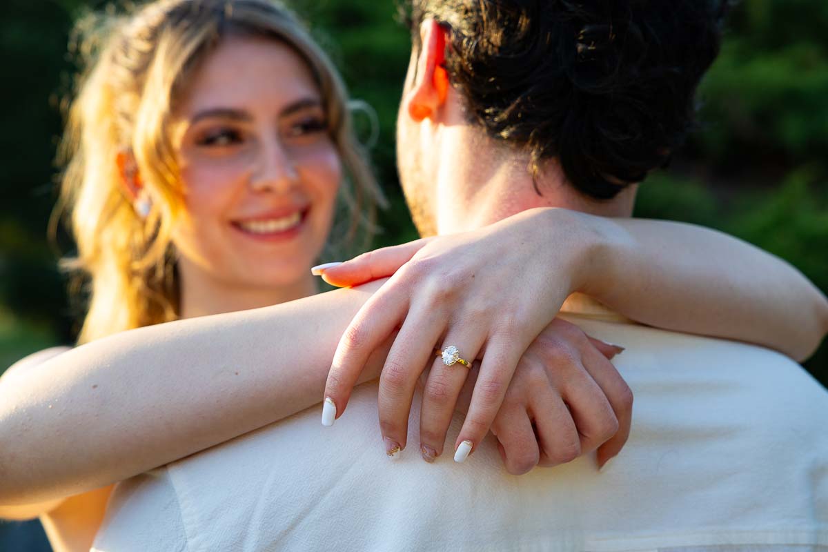 Ring closeup with photo taken from behind the couple showing the beautiful smile and the diamond ring