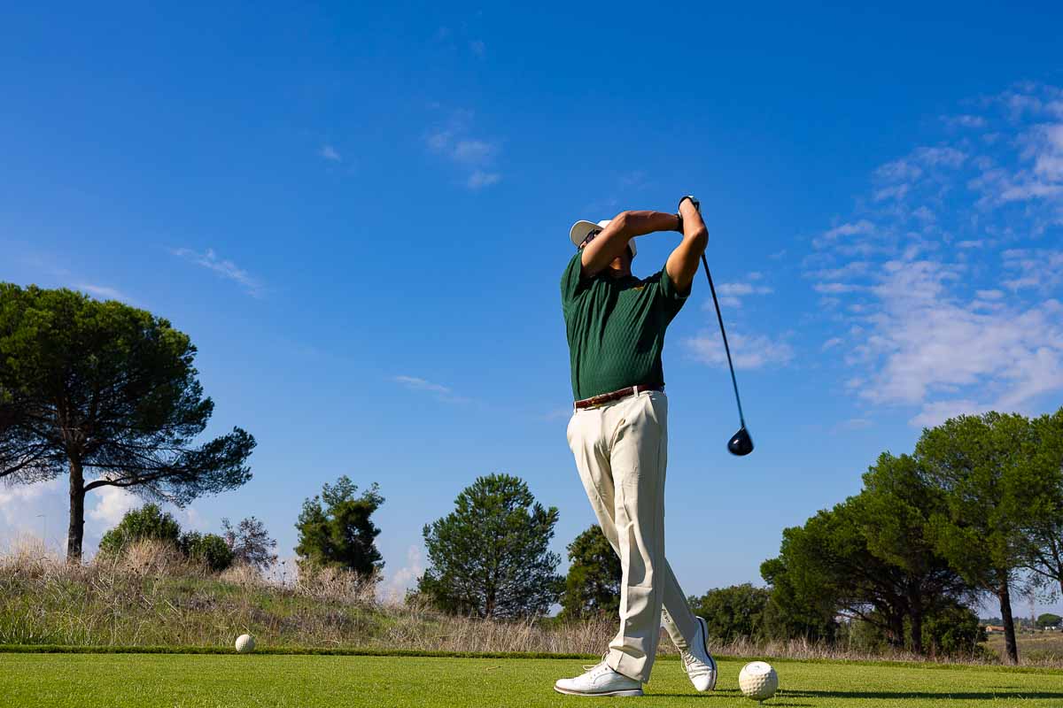 Low-angle view of a player teeing off – dynamic shot capturing the swing’s motion and the trajectory of the ball against the sky