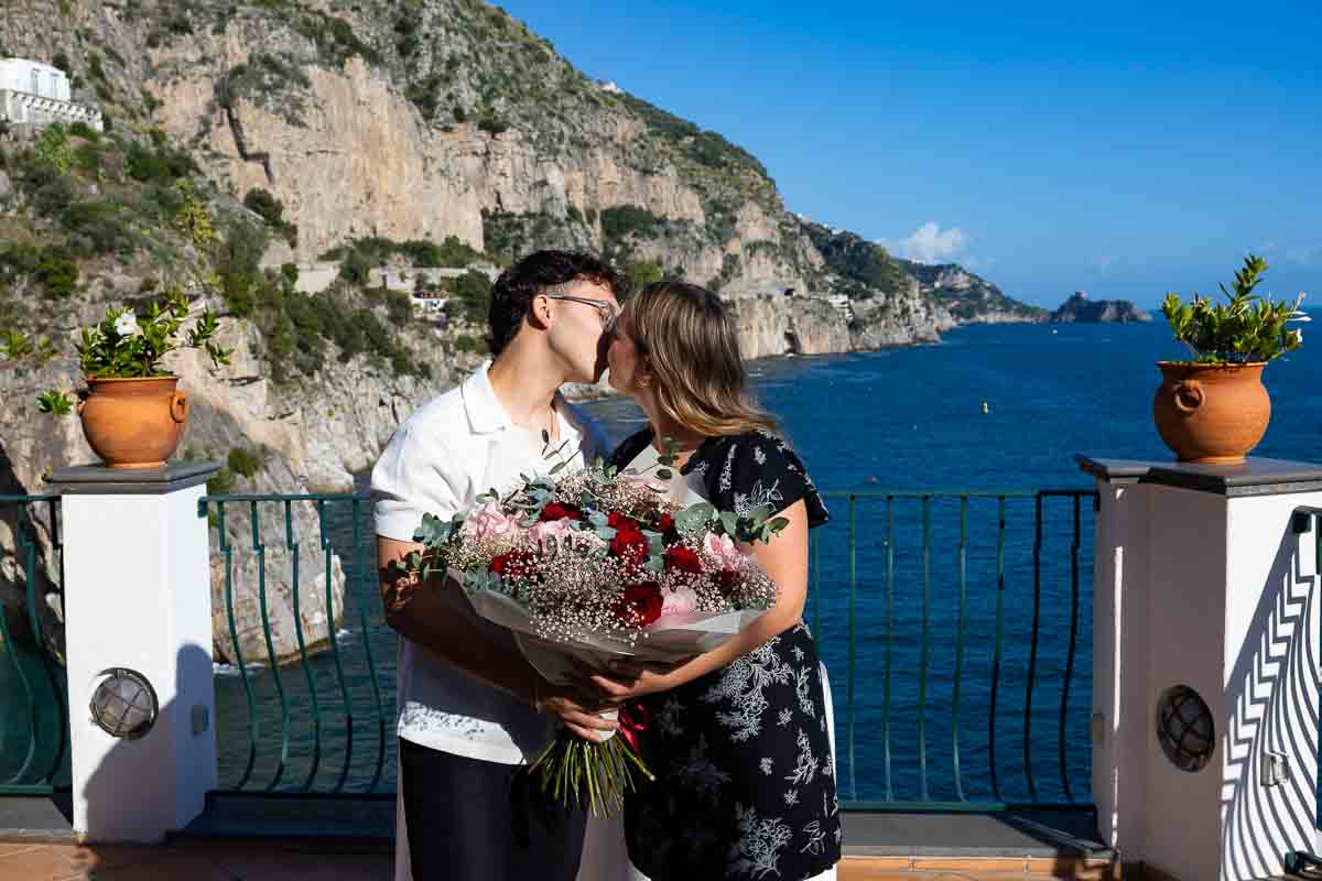Couple portrait photography holding a stunning bouquet of roses kissing 