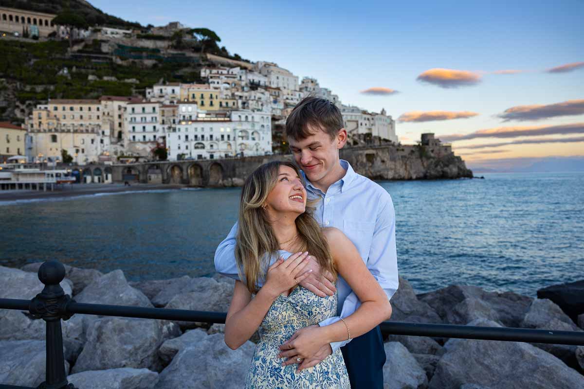 Couple portrait picture image while looking at each other with the sea and town wight behind them sunset image