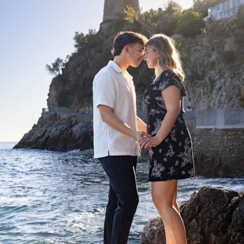 Standing together by the sea during an engagement pgotoshoot next to the water with the saracen tower in the back