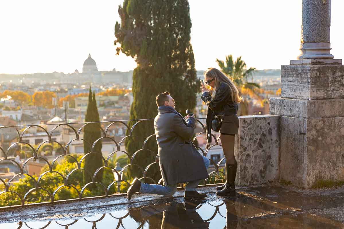 Fiancee kneeling down to ask the Big question before the scenic view of the eternal city capital of Italy