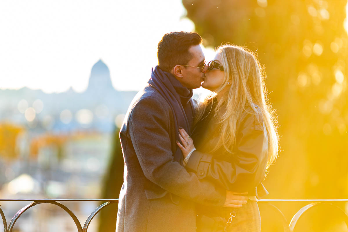 Golden hour light lighting an engagement photo shoot snapped at a vintage point with view over the roman skyline