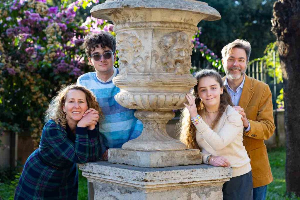 Family portrait picture posed next to an ancient roman vase each participant taking on a difference stance for the photography session Italy by a professional photographer