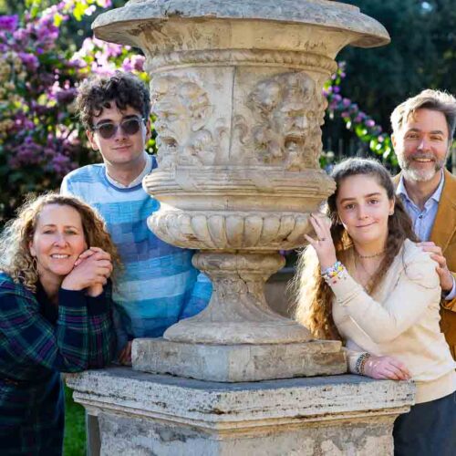 Family portrait picture posed next to an ancient roman vase each participant taking on a difference stance for the photography session Italy by a professional photographer