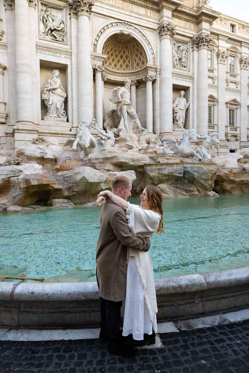 Couple photographed near the Trevi Fountain in Rome during a winter engagement session with soft morning light and stillness 