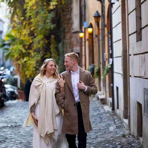 Walking on cobblestone alleyway streets holding on to each other while on a photoshoot in Rome Italy