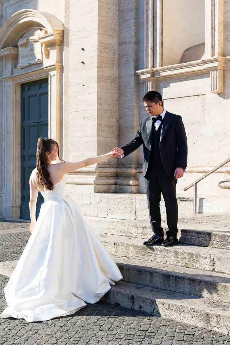 Wedding pictures of a couple posing by a beautiful white marble church in Rome.