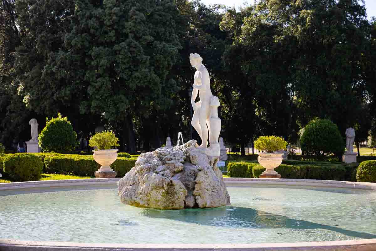 Image of the water fountain with the central statue immersed in lush greenery